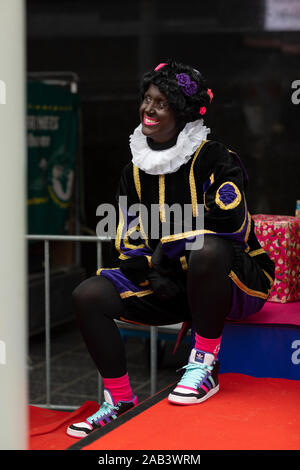Eindhoven (Pays-Bas), 23 novembre 2019. Zwarte Piet portant son costume coloré avec détails dorés et souriant à la petite enfance à welc Banque D'Images