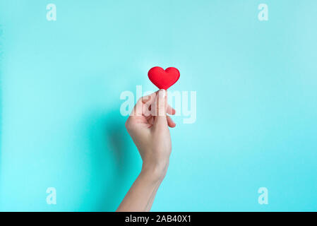 Hand holding Red Heart, fond bleu avec copie espace. La Saint-Valentin, l'amour, la charité et la gratitude des concept. Banque D'Images