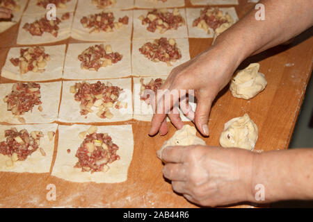 Processus national de cuisson des aliments. Manty dans un manteau en acier inoxydable. Cuisiner à la maison. Plat cru de pommes de terre et de viande à l'intérieur. Banque D'Images