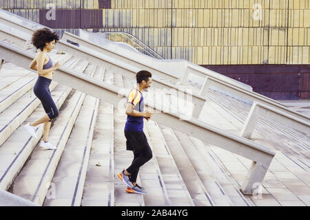 Jeune femme latine et afro-américain d'exécution formation homme sportif dans les escaliers de la ville. fitness, urban sports d'entraînement et de vie sain concept, Banque D'Images