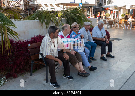 Les vieux hommes assis sur un banc de rue appréciant leur journée à Estepona, Espagne Banque D'Images