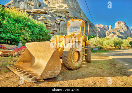 Vue latérale d'excavatrice jaune pour les travaux de construction le long de la route dans un chantier de construction. Les travaux en cours, une machine industrielle. Sur les montagnes Banque D'Images