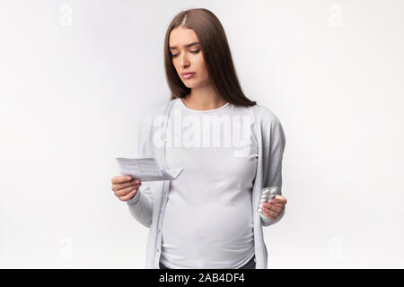 Dame enceinte l'enseignement de la lecture pour les comprimés debout, Studio Shot Banque D'Images