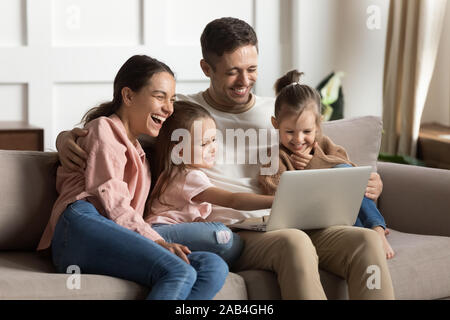 Les parents séropositifs et les enfants filles rient à l'aide d'ordinateur portable à la maison Banque D'Images