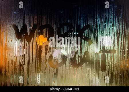 Les mots faire de l'écrit sur la vitre humide nuit close-up avec l'arrière-plan flou. Banque D'Images