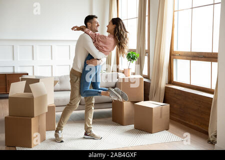 Heureux mari excité de levage femme célébrant le jour du déménagement avec des cases Banque D'Images