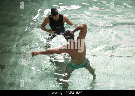 L'homme de prendre des cours de natation avec un enseignant. Banque D'Images