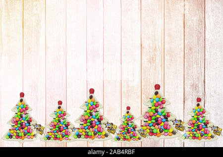 Des assiettes en forme d'arbres de Noël avec des bretzels et des bonbons décorent le fond en bois. Jouet en verre amusant et décorations d'arbre de Noël Banque D'Images