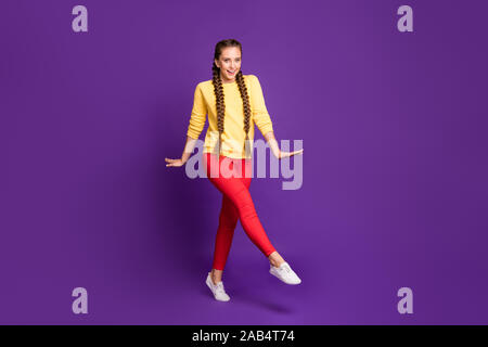 Photo pleine longueur de funny lady millénaire walking down street longues tresses amazing chaude journée ensoleillée porter pull jaune occasionnels pantalon rouge isolé Banque D'Images