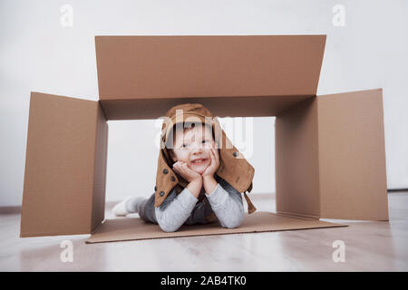 La petite enfance ludique. Petit garçon s'amuser grâce à la boîte de carton. Garçon prétendant être pilote. Little Boy and girl having fun at home Banque D'Images