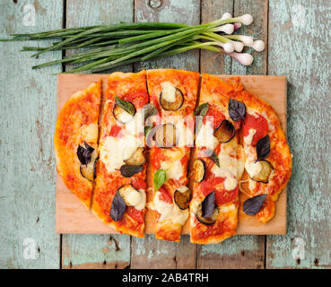 Pizza végétarienne avec des feuilles de basilic et l'aubergine coupée en bandes avec oignon de printemps sur fond bleu en bois miteux vue supérieure Banque D'Images