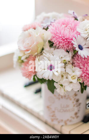 Bouquet de fleurs dans une belle boîte sur un piano blanc. Bouquet d'asters, hortensias et marguerites. Bouquet de mariée. Banque D'Images