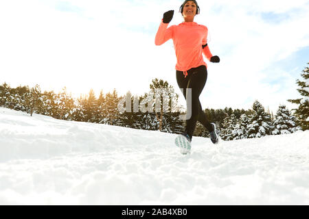 Smiling healthy woman jogging en forêt enneigée Banque D'Images