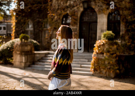 Jolie jeune femme marche dans le parc de l'automne sur une journée ensoleillée Banque D'Images