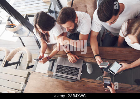 Un groupe de jeunes avec des gadgets et un ordinateur portable organiser une séance de brainstorming et de communiquer les uns avec les autres. Le concept de l'élaboration d'une jeune entreprise Banque D'Images