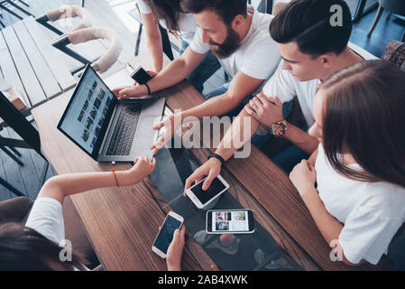 Un groupe de jeunes avec des gadgets et un ordinateur portable organiser une séance de brainstorming et de communiquer les uns avec les autres. Le concept de l'élaboration d'une jeune entreprise Banque D'Images