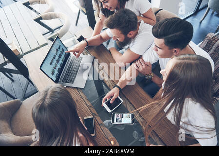 Un groupe de jeunes avec des gadgets et un ordinateur portable organiser une séance de brainstorming et de communiquer les uns avec les autres. Le concept de l'élaboration d'une jeune entreprise Banque D'Images
