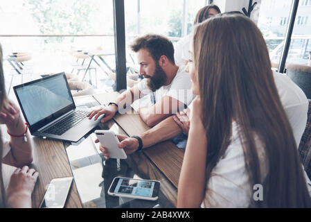 Un groupe de jeunes avec des gadgets et un ordinateur portable organiser une séance de brainstorming et de communiquer les uns avec les autres. Le concept de l'élaboration d'une jeune entreprise Banque D'Images