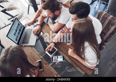 Un groupe de jeunes avec des gadgets et un ordinateur portable organiser une séance de brainstorming et de communiquer les uns avec les autres. Le concept de l'élaboration d'une jeune entreprise Banque D'Images