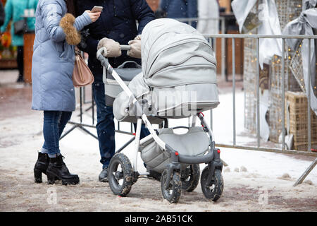 Jeune mère de famille avec le père et l'enfant dans la poussette dehors à la journée d'hiver Banque D'Images