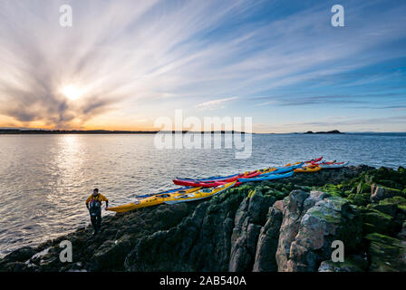 Lothian Club de kayak de mer sur le rivage avec des kayaks au coucher du soleil, l'île d'agneau, Firth of Forth, Ecosse, Royaume-Uni Banque D'Images
