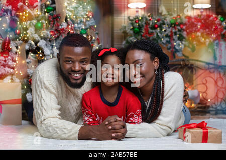 Famille de trois afro amour lying on floor near Christmas Tree Banque D'Images