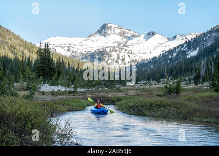 Une pagaie kayak gonflable sur un flux à travers une prairie subalpine dans Oregon's Eagle Cap désert. Banque D'Images