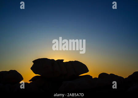 D'étranges formations rocheuses découpé sur le coucher du soleil le long de la Côte de granit rose / Côte de Granit Rose, Côtes d'Armor, Bretagne, France Banque D'Images