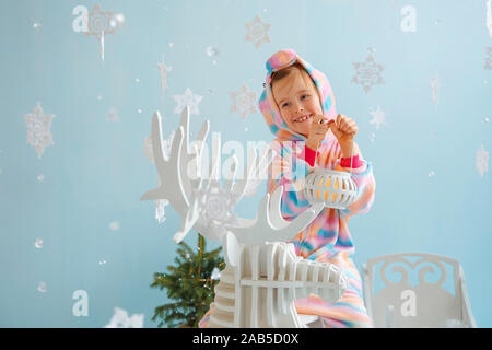 Little girl in red sneakers et cerf de Noël à côté des boîtes à cadeaux. Banque D'Images