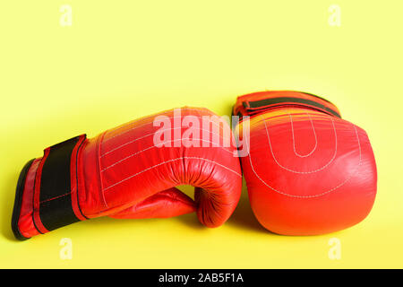 Paire de gants de boxe rouge pour thai wrestling isolé sur fond jaune citron lumineux. Concept de salle de sport et d'une formation active Banque D'Images