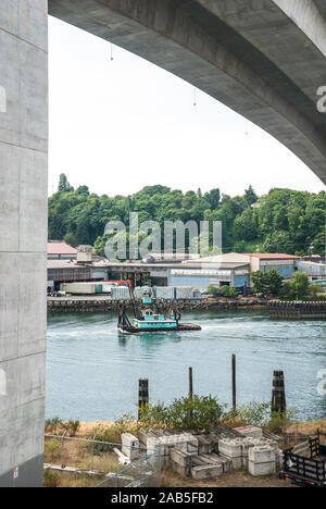 Un bateau de travail au-delà de la voile sur des barges grues près du pont West Seattle (Jeanette Williams Memorial Bridge) dans la région de West Seattle, Washington. Banque D'Images