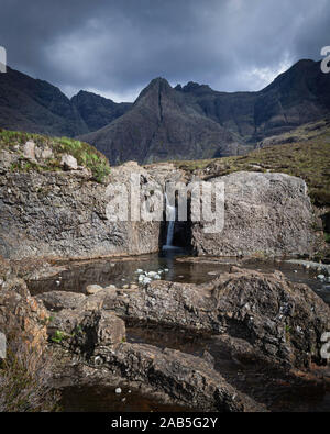 Moody ciel au-dessus de montagnes et petite chute en terrain rocheux en premier plan.Conte de piscines sur Ile de Skye, Ecosse, UK.attraction de touristes populaires. Banque D'Images