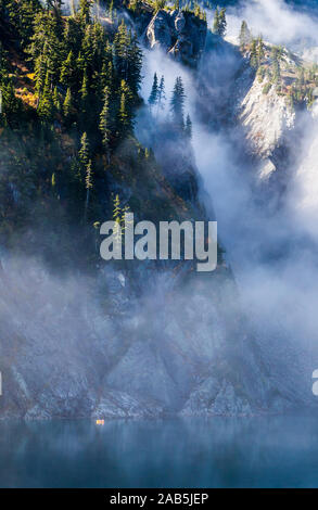 Un homme dans un petit radeau pneumatique de l'aviron sur le lac de la neige au-dessus de Snoqualmie Pass dans la partie centrale de la chaîne des Cascades dans l'État de Washington, USA. Banque D'Images