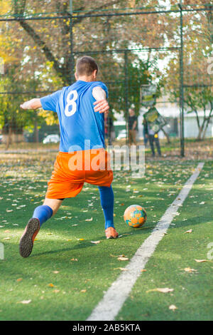 Un joueur de football effectue une action jouer sur un terrain de soccer. Tous les joueurs portent des vêtements sans marque. Banque D'Images