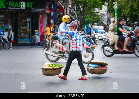 Hanoi, Vietnam - 11 octobre 2019 : avec un pôle de transport en bois transportant des marchandises à travers une route très fréquentée à Hanoi, en Asie Banque D'Images