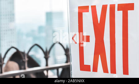 Signal de sortie avec des lettres rouges et fond blanc. Clôture et out-of-focus bâtiments dans l'arrière-plan. Manhattan, New York, USA. Banque D'Images