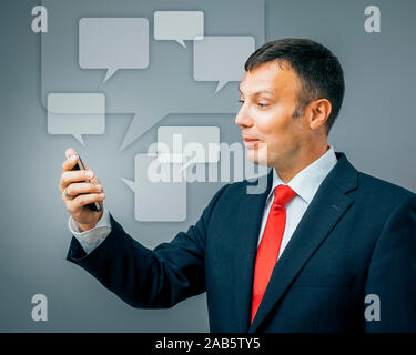 Geschaeftsmann Ein attraktiver im Anzug, der ein Mobiltelefon in der Hand hat Banque D'Images