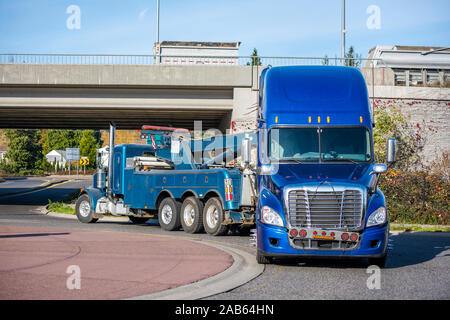 Big Rig Mobile dépanneuse avec rampe de levage et de trois essieux arrière de camion de conduite cassée gros camion de remorquage bleu semi tracteur routier avec l'éclairage de secours sur t Banque D'Images