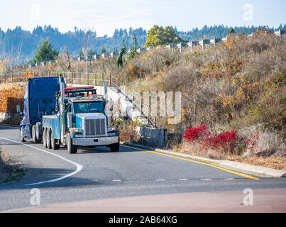 Big Rig Mobile dépanneuse avec rampe de levage et de trois essieux arrière de camion de conduite cassée gros camion de remorquage bleu semi tracteur routier avec l'éclairage de secours sur t Banque D'Images