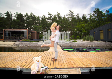 Jeune couple amoureux bisous sur une jetée en bois. Lovestory sur l'embarcadère. Banque D'Images