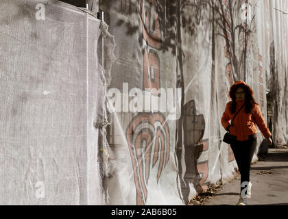 Belgrade, Serbie, May 24, 2019 : une femme marche dans la rue à côté d'un mur couvert d'échafaudage Banque D'Images