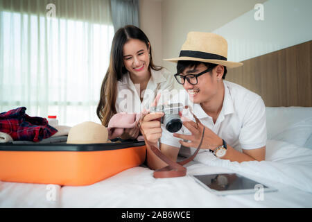 Happy Asian couple déballage de valise sur le lit dans la chambre quand ils arrivent dans chambre d'hôtel et le mensonge et à la photo en voyage voyage à l'appareil photo. Bac asiatique Banque D'Images