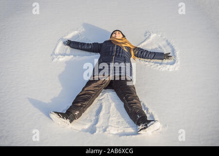 Femme vêtue d'une chaleureuse de la forêt d'hiver froid neige rend angel figure au parc. Copier le texte de l'espace Banque D'Images