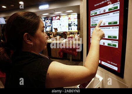 La ville de Quezon, Philippines - 24 novembre 2019 : Les clients du restaurant fast food international populaires essayer de nouvelles et meilleures de la commande système où ils ne peuvent Banque D'Images