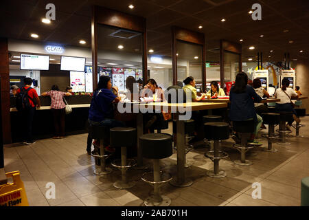 La ville de Quezon, Philippines - 24 novembre 2019 : Les clients manger et déguster vos repas dans la salle à manger d'un restaurant-minute. Banque D'Images