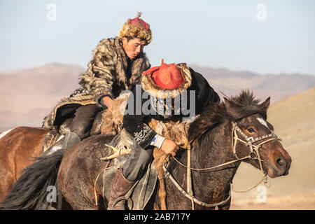 Les chasseurs eagle kazakhs prenant part à un match de lutte traditionnelle. Deux lutteurs à cheval commencer tirant sur une peau de mouton, celui qui le récupère, je Banque D'Images