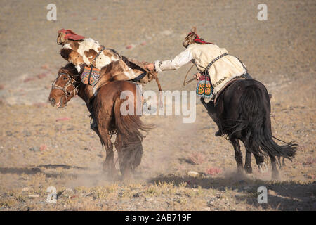 Les chasseurs eagle kazakhs prenant part à un match de lutte traditionnelle. Deux lutteurs à cheval commencer tirant sur une peau de mouton, celui qui le récupère, je Banque D'Images