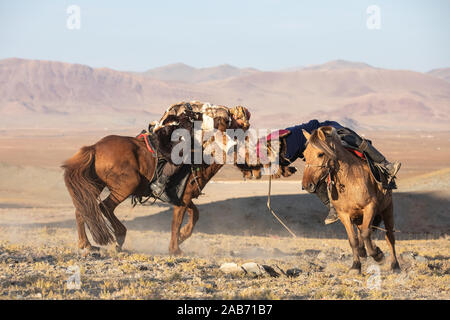 Les chasseurs eagle kazakhs prenant part à un match de lutte traditionnelle. Deux lutteurs à cheval commencer tirant sur une peau de mouton, celui qui le récupère, je Banque D'Images