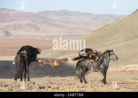 Les chasseurs eagle kazakhs prenant part à un match de lutte traditionnelle. Deux lutteurs à cheval commencer tirant sur une peau de mouton, celui qui le récupère, je Banque D'Images