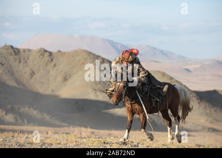 Jeu mongole traditionnelle où un cavalier sur l'objectif d'aller chercher une serviette depuis le sol à pleine vitesse au galop. Ulgii, la Mongolie. Banque D'Images